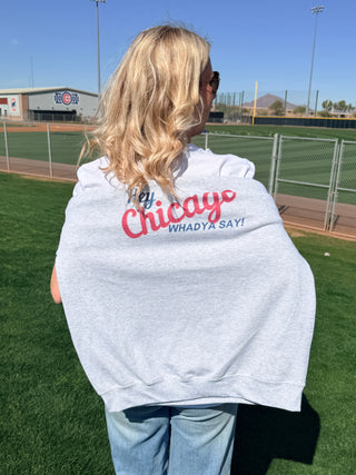 Person wearing a white sweatshirt with Hey Chicago Whadya Say red text on a sports field