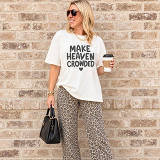 Woman wearing the Make Heaven Crowded Comfort Colors Christian tee in Ivory with leopard wide-leg jeans