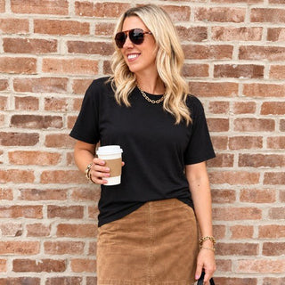 Woman wearing the Favorite Soft Solid Bella+Canvas Tee in Black with a camel mini skirt
