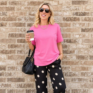 Woman wearing the Favorite Soft Solid Bella+Canvas Tee in Charity Pink with black polka dot pants