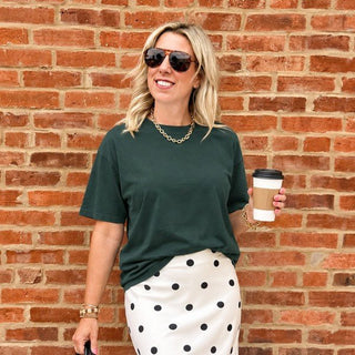 Woman wearing the Favorite Soft Solid Bella+Canvas Tee in Forest with a polka dot satin skirt